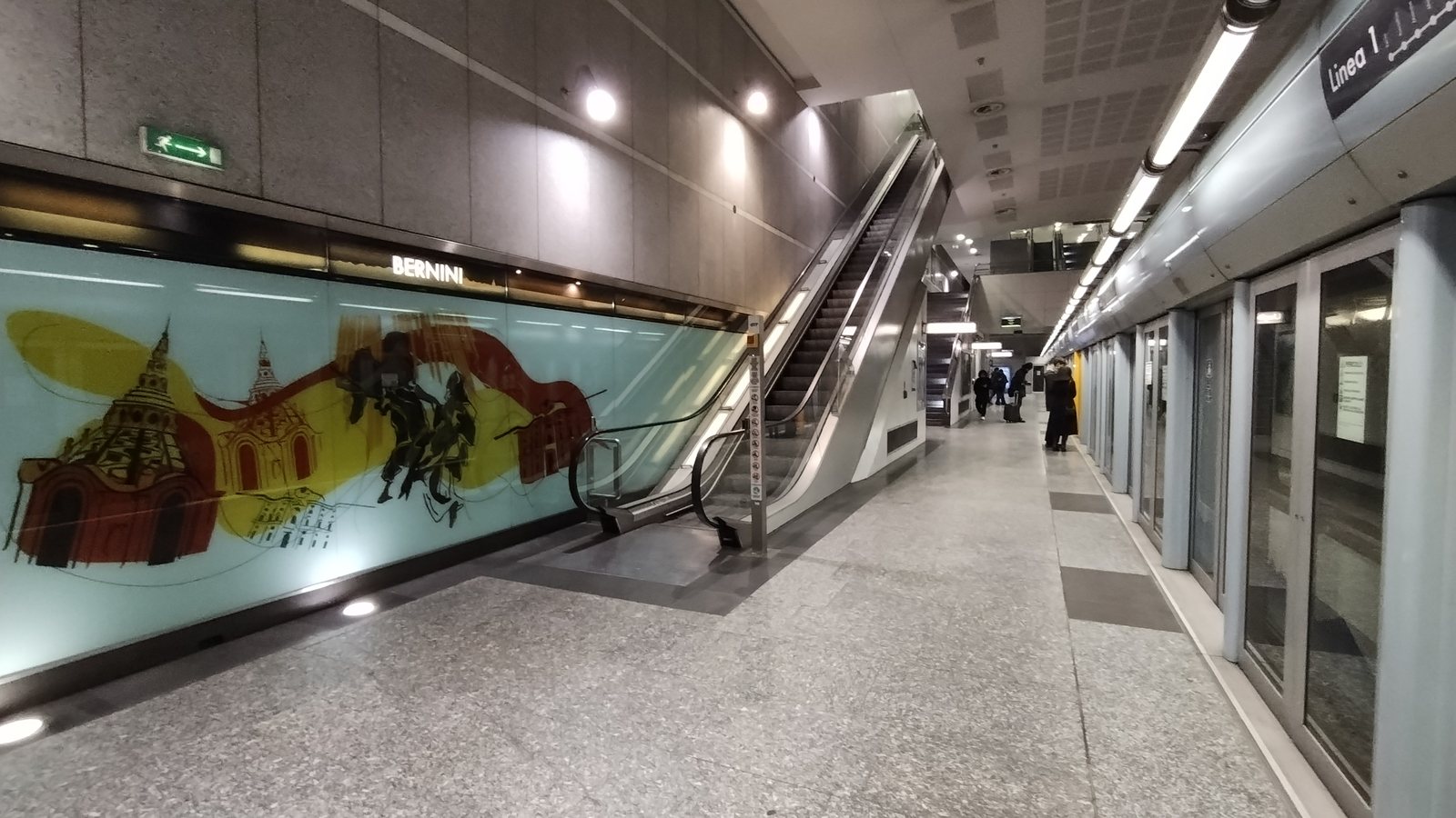 Banchina della stazione Bernini con la targa BERNINI e un treno fermo dietro le porte di banchina
