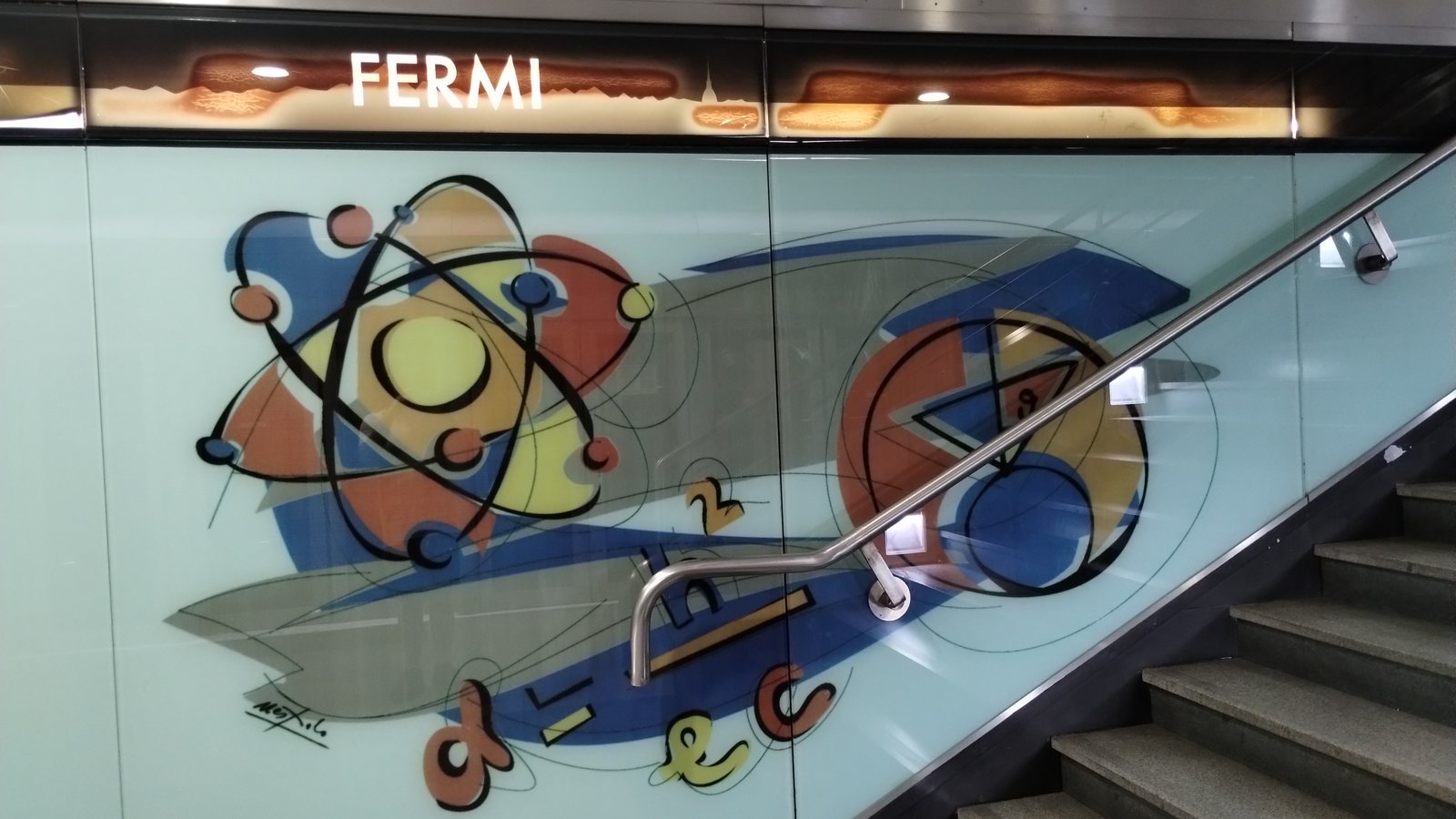 Targa con la scritta FERMI sulla parete decorata della banchina della stazione Fermi