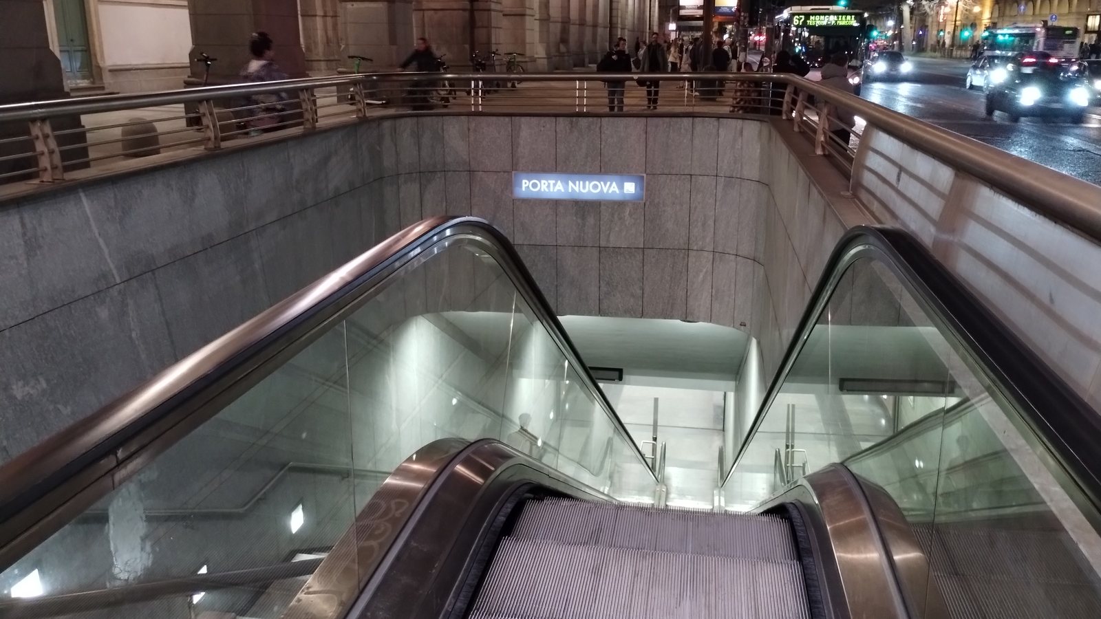 Scale mobili di accesso alla stazione Porta Nuova con la targa PORTA NUOVA, di notte, davanti alla stazione ferroviaria