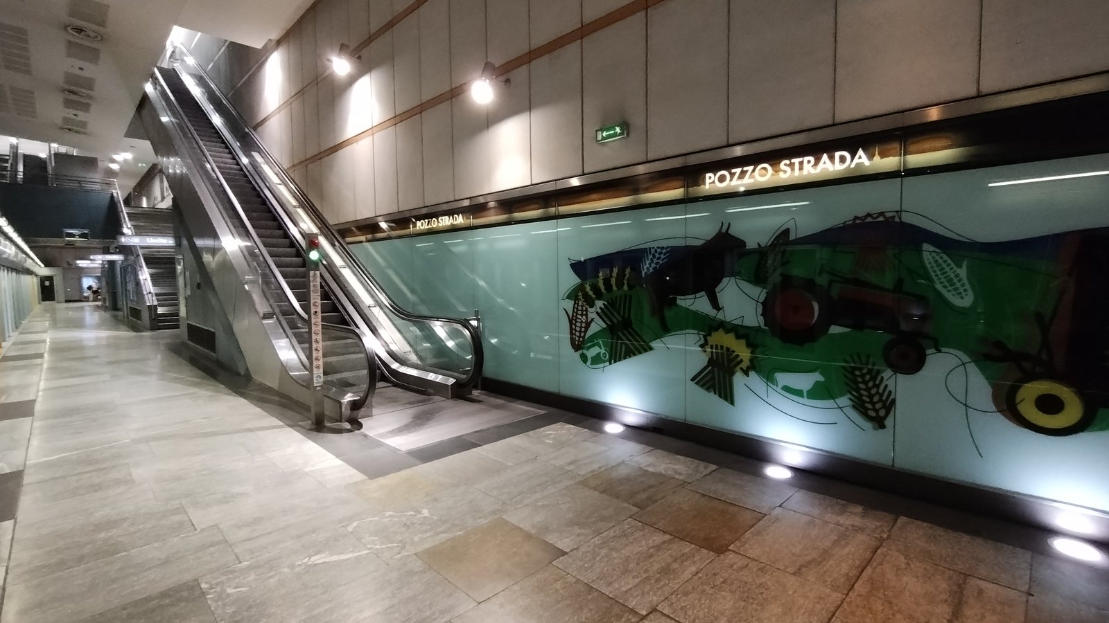Scale mobili e targa POZZO STRADA sulla banchina della stazione Pozzo Strada